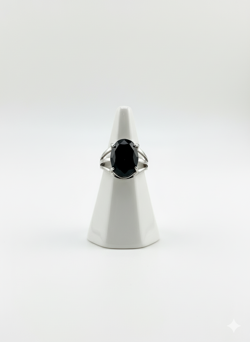 Ring with a black gemstone on a white stand against a white background