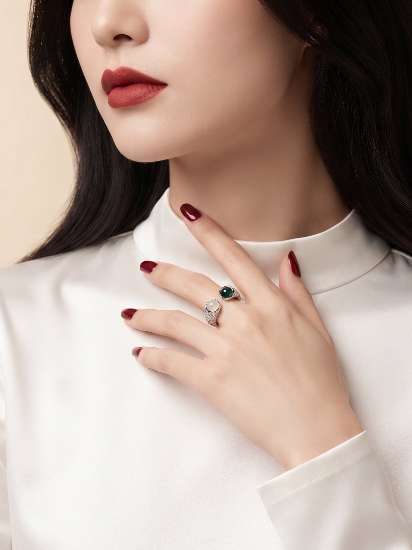 A close-up of a woman wearing a white high-neck blouse, showcasing a silver ring with a green oval gemstone on her ring finger.