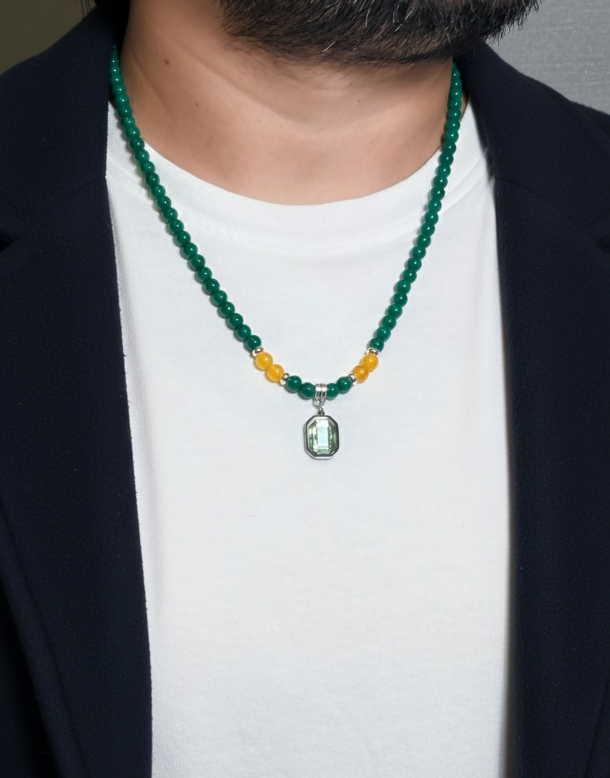 Person wearing a green beaded necklace with a pendant on a plain background