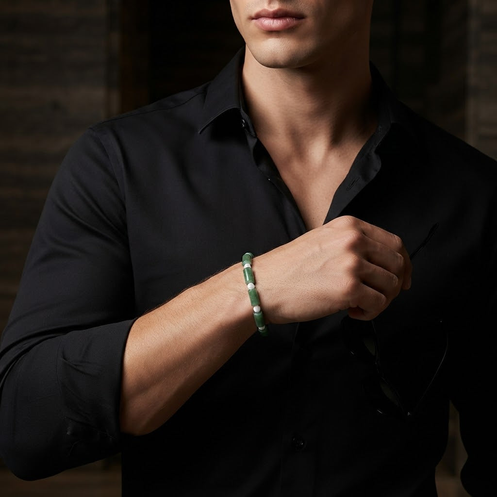 A man wearing a black button-down shirt and adjusting his collar, wearing a green beaded bracelet on his wrist.