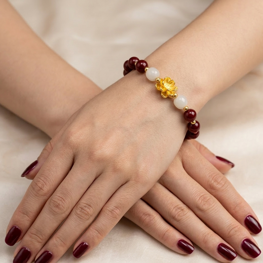 Bracelet with red and gold beads on a wrist with maroon nail polish.