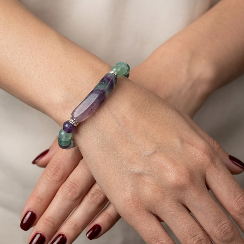 Close-up of a hand wearing a colorful beaded bracelet on a neutral background