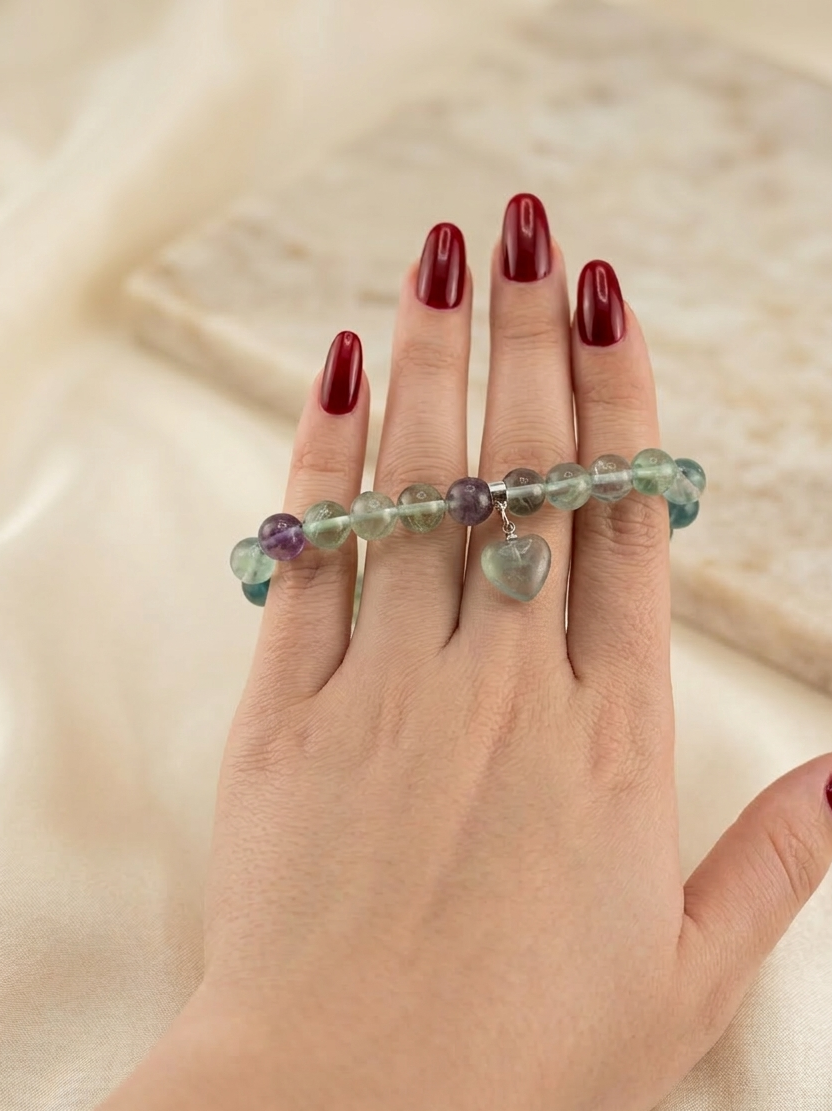 Hand wearing a colorful beaded bracelet on a beige background