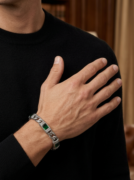Person wearing a silver bracelet with green stones on a black background