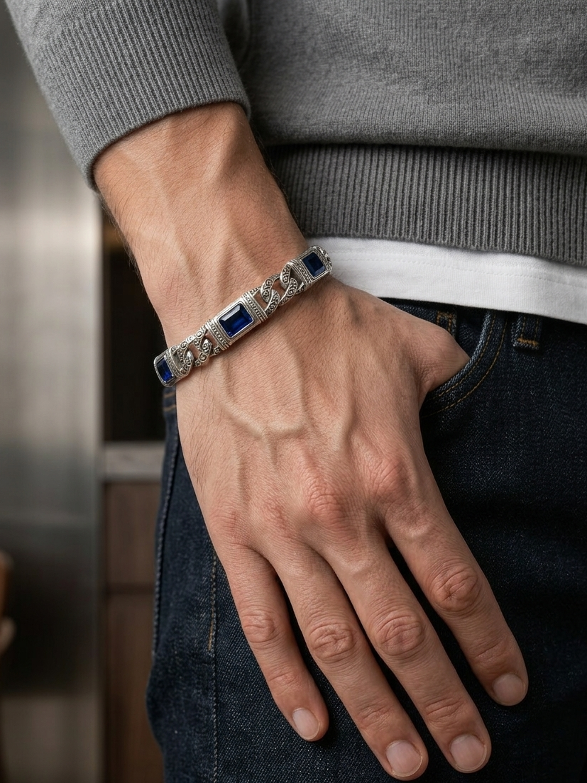 Hand wearing a bracelet with blue stones and silver accents, against a neutral background.