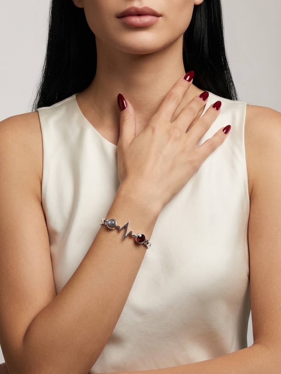 A close-up of a woman wearing a silver-toned bracelet with a heartbeat line design and small heart-shaped charms, paired with a cream-colored sleeveless top.