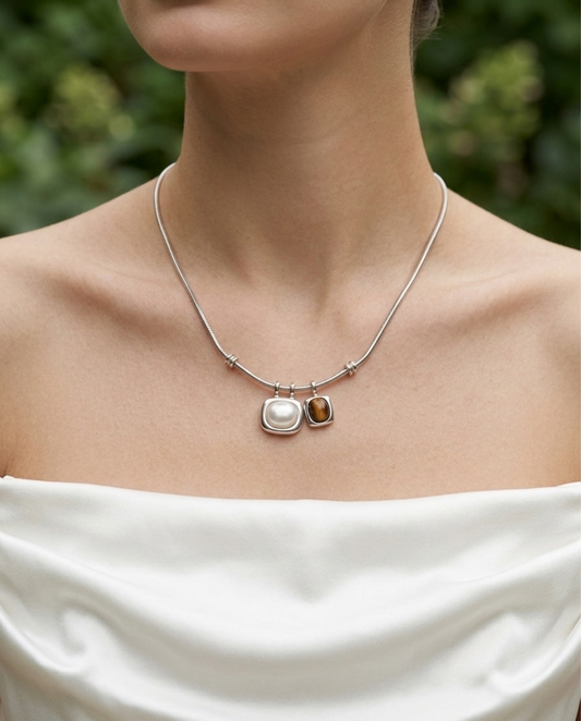 Necklace with two pendants worn by a person against a blurred green background
