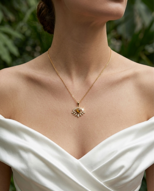 Woman wearing a gold necklace with a pendant against a blurred green background