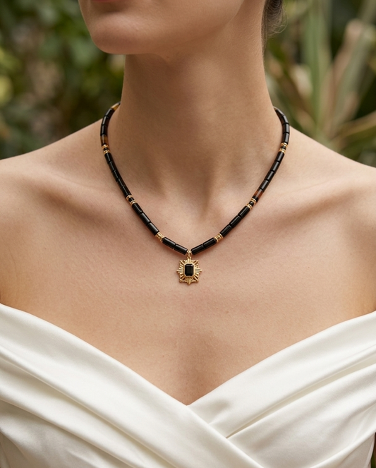 Necklace with a pendant worn by a person in a white dress against a blurred natural background
