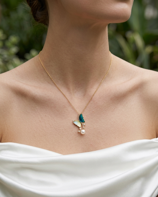 Necklace with a pendant featuring a butterfly and pearl on a blurred natural background