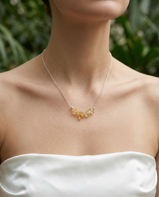 Gold necklace worn by a person with a blurred green background