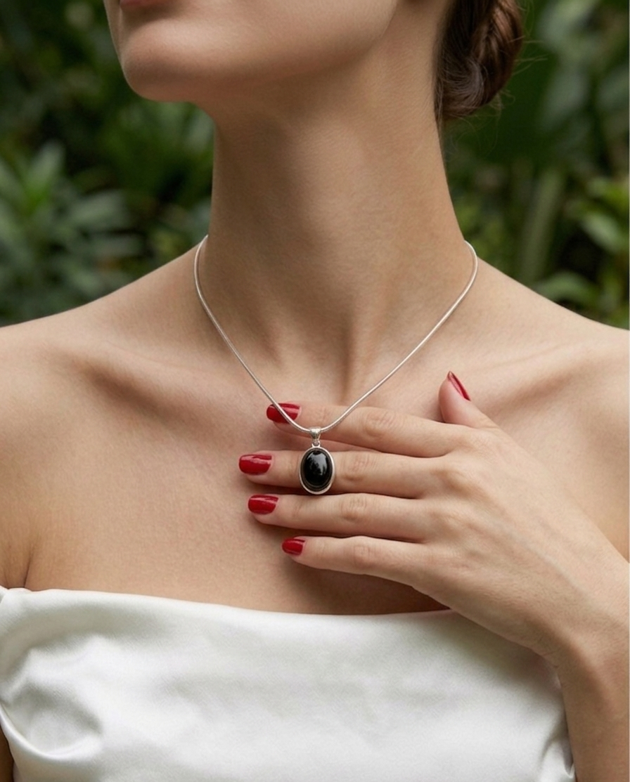 Woman wearing a necklace with a pendant against a blurred green background