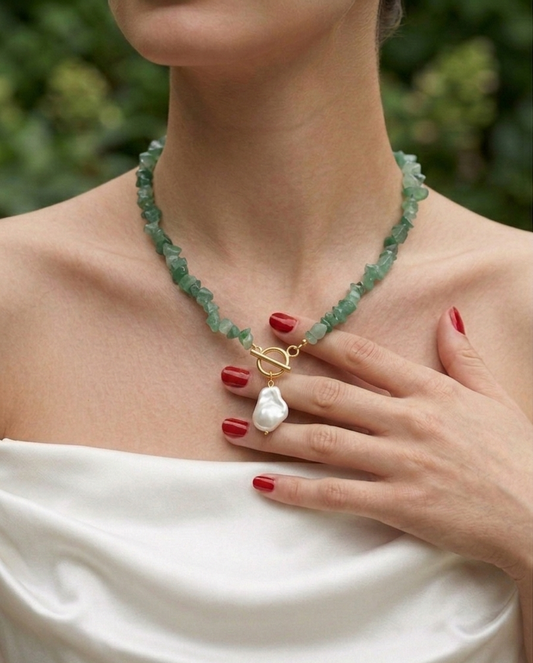 Necklace with a pearl pendant worn by a person with a blurred natural background