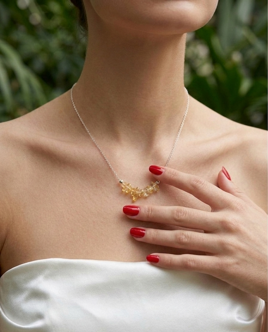 Woman wearing a delicate necklace with a green leafy background