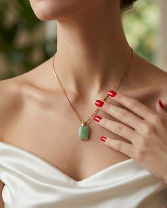 Necklace with a green pendant worn by a person in a white top.