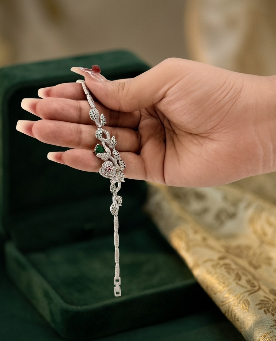 Hand holding a delicate silver bracelet with green gemstone against a blurred background