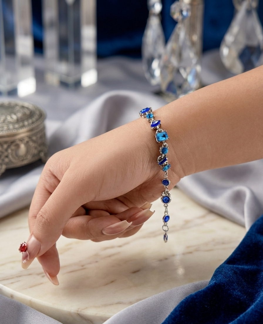 Hand wearing a blue beaded bracelet on a marble surface with decorative items in the background