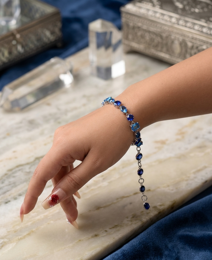 Hand wearing a blue beaded bracelet on a marble surface with a blue fabric background