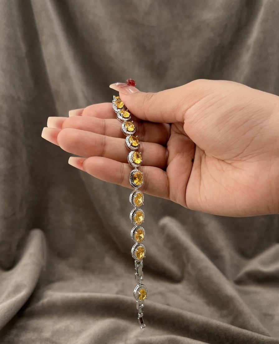 Hand holding a bracelet with yellow gemstones against a brown fabric background