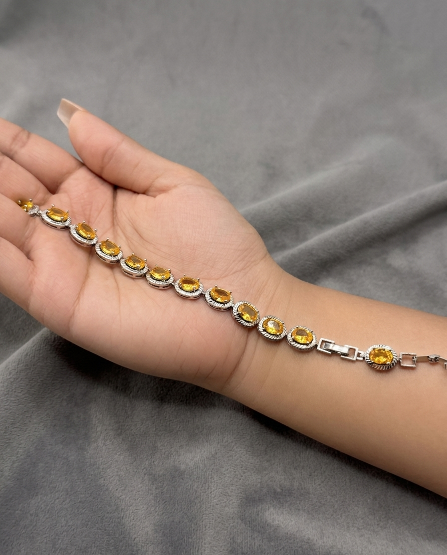 Hand wearing a silver bracelet with yellow gemstones on a gray fabric background