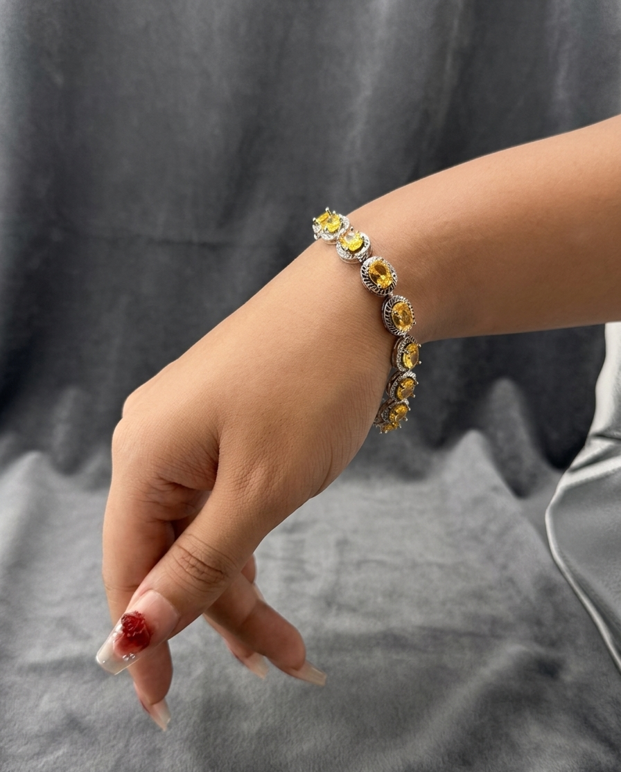 Hand wearing a bracelet with yellow gemstones on a gray background