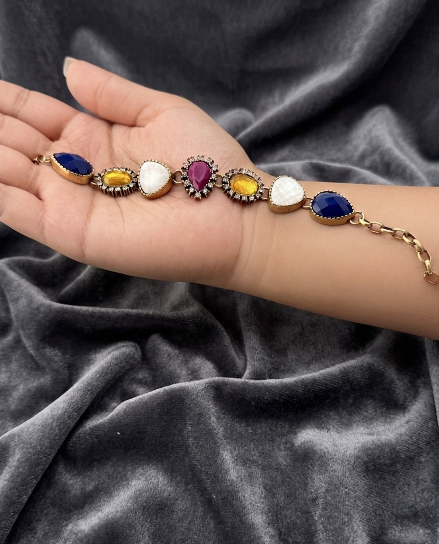 Bracelet with colorful gemstones held in a hand on a dark fabric background