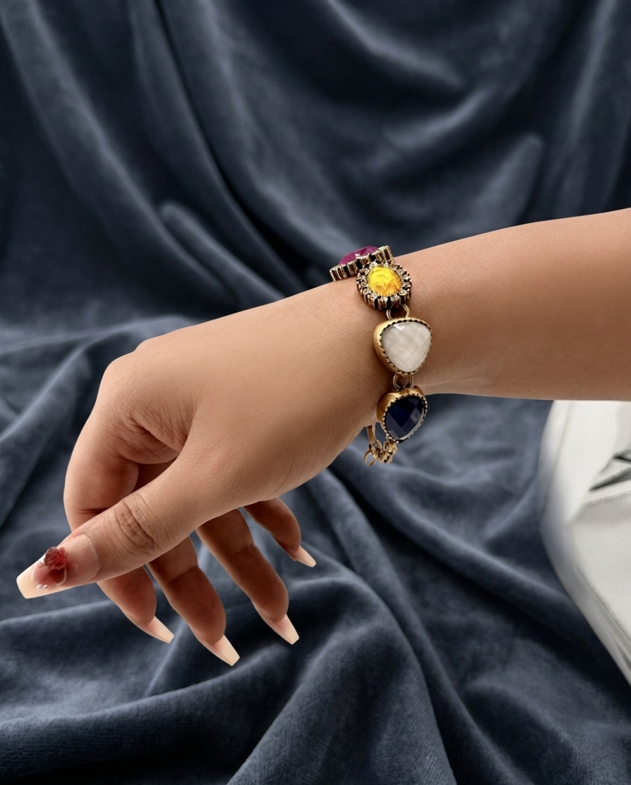 Hand wearing a bracelet with charms on a dark fabric background