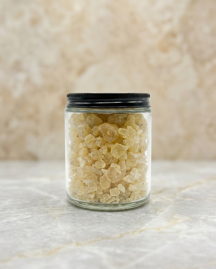 Clear glass jar with black lid containing a light-colored substance on a marble surface.