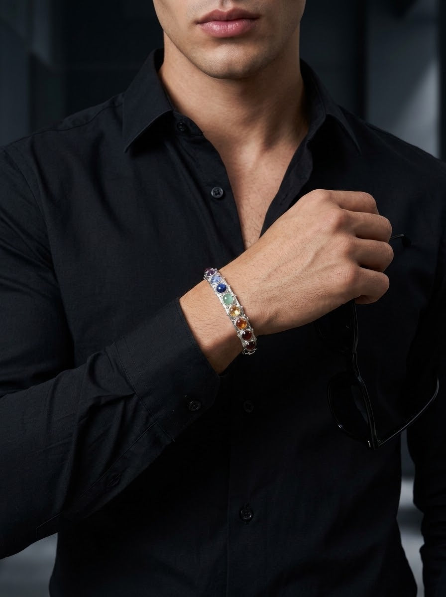 A close-up of a man wearing a silver-toned bracelet with colorful gemstones, including blue, green, yellow, and orange, while wearing a black button-down shirt.