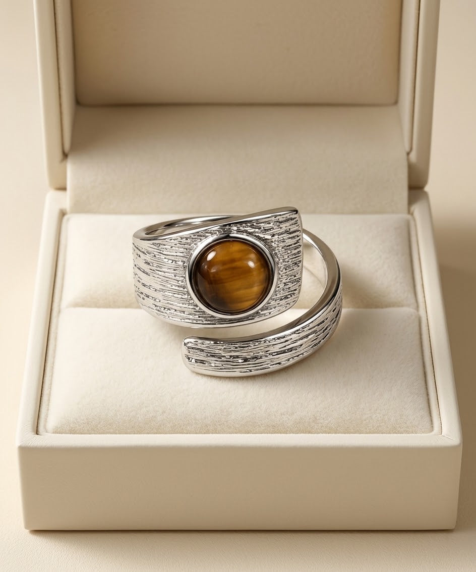 A textured silver wrap ring with a round brown tiger's eye stone, presented in an open cream-colored jewelry box.