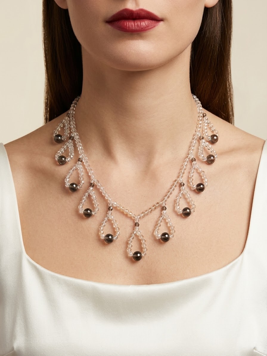 A close-up of a model wearing a statement necklace with teardrop-shaped clear crystal clusters and dark brown spherical beads on a delicate chain.