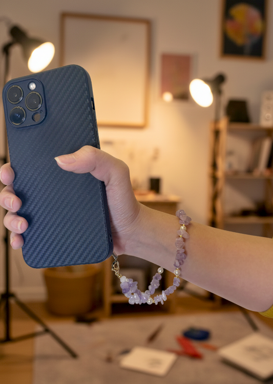 Amethyst crystal phone charm on wrist while holding phone