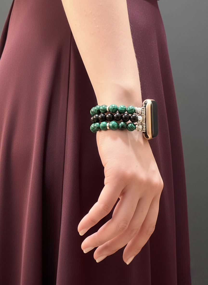 Close-up of a hand wearing a green beaded bracelet on a plain background