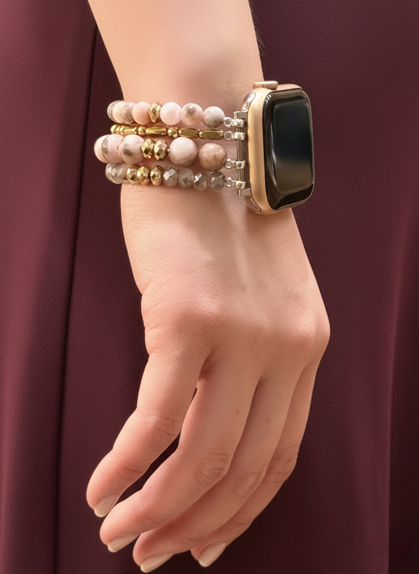 Hand wearing a smartwatch with multiple bracelets on a plain background
