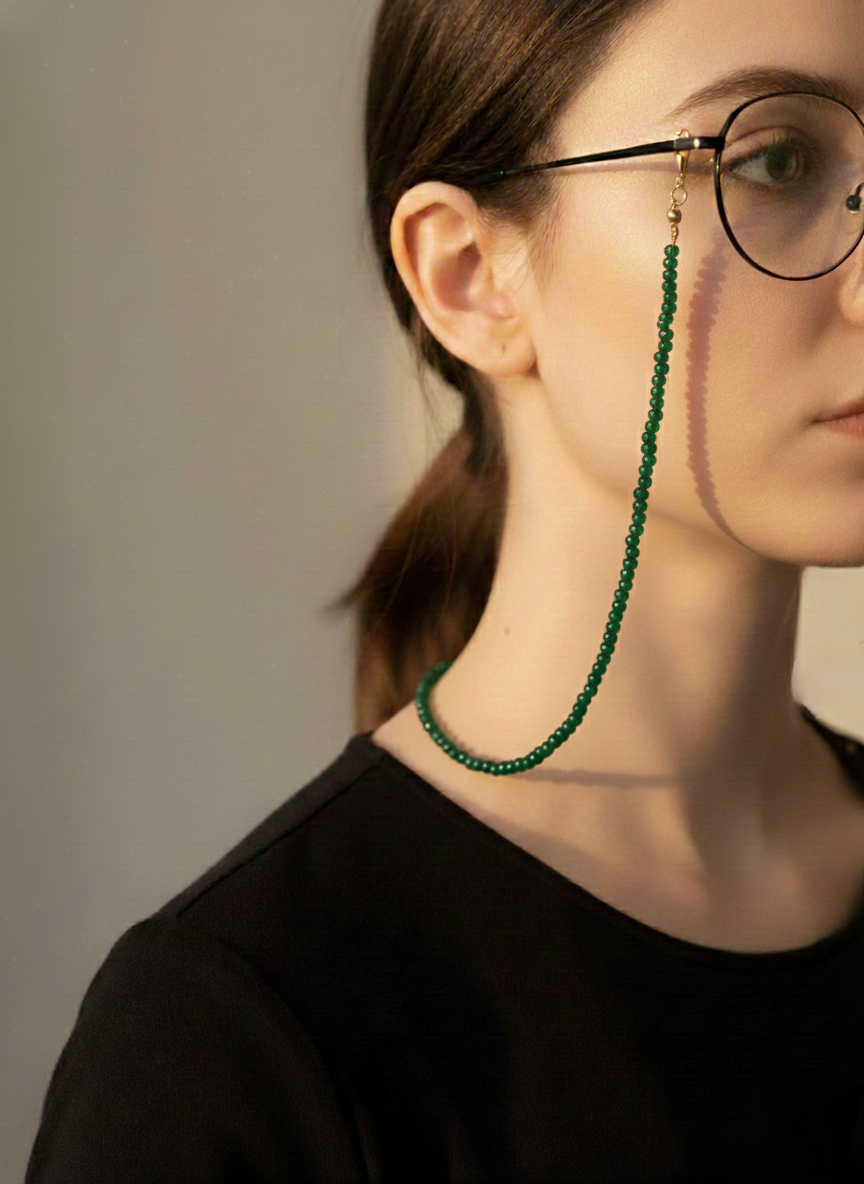 Person wearing a green beaded eyeglass chain against a neutral background