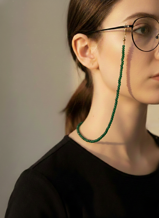Person wearing a green beaded eyeglass chain against a neutral background