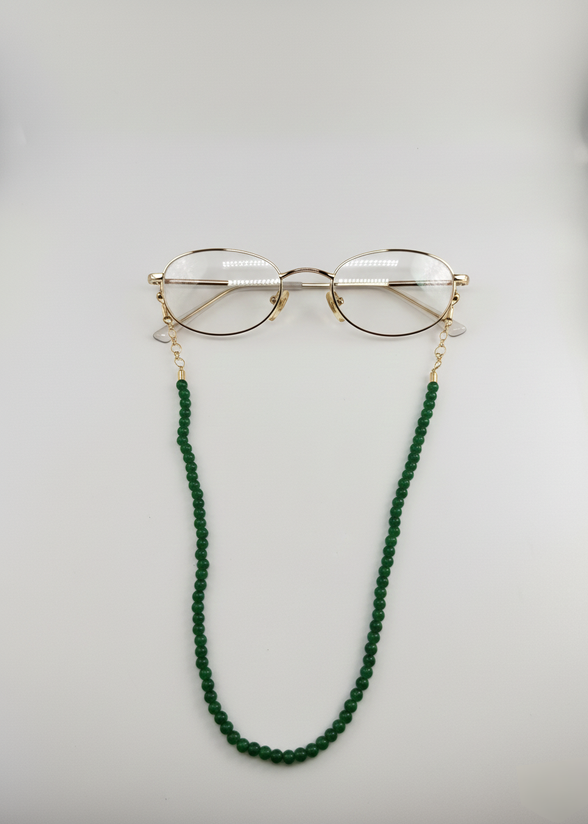 Gold-framed glasses with a green beaded chain on a light gray background