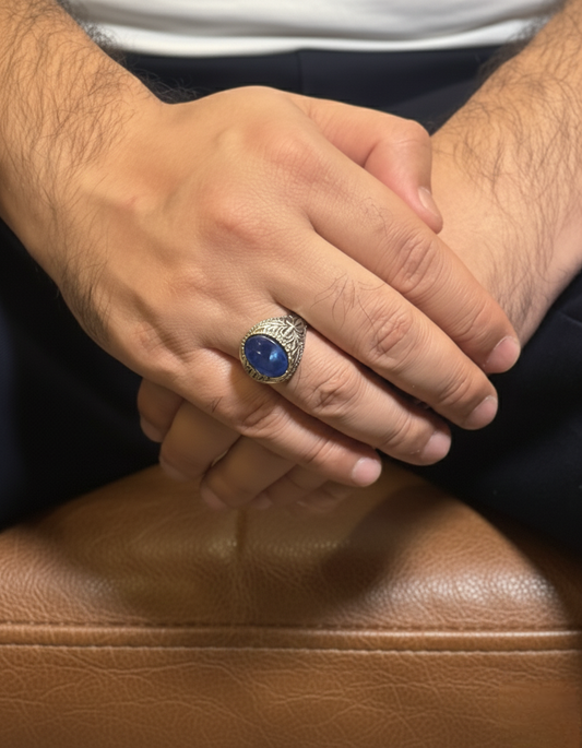 Hand wearing a ring with a blue stone on a brown leather surface