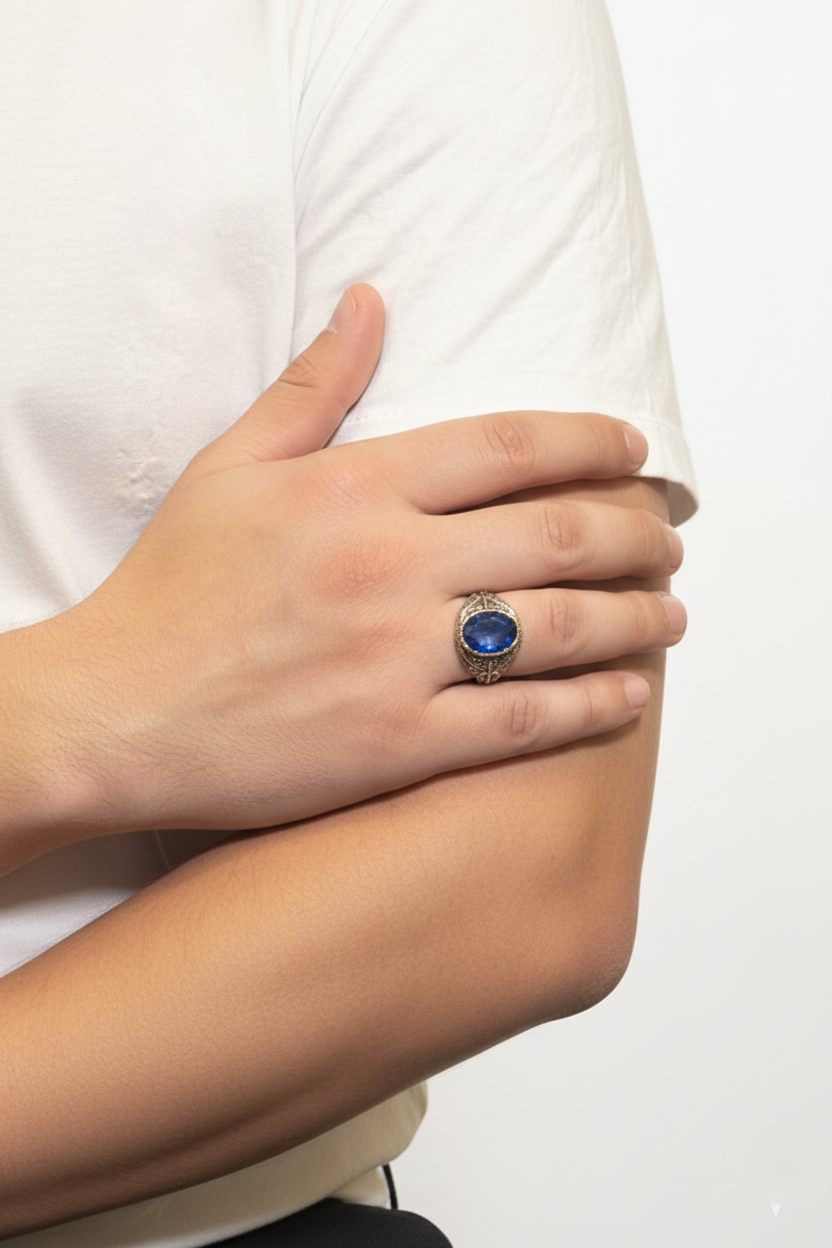 Hand wearing a ring with a blue gemstone on a white background