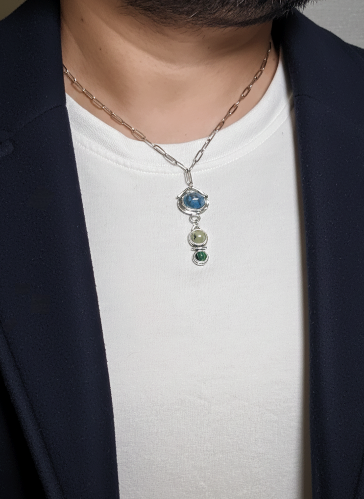 Person wearing a necklace with a pendant on a plain background