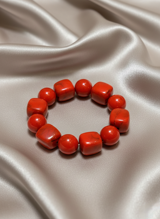 Red beaded bracelet on a satin surface