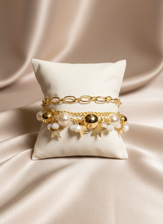 Gold bracelet with pearls and charms on a beige pillow