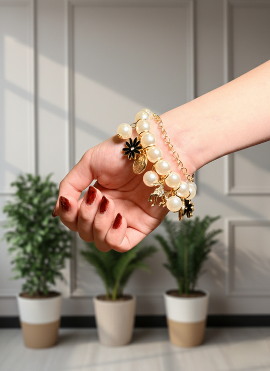 Person wearing a pearl bracelet with a decorative charm, standing in front of potted plants.