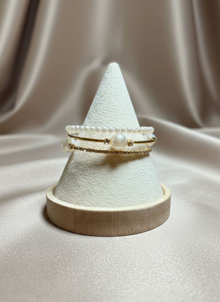 Two pearl rings on a cone-shaped jewelry stand against a beige fabric background