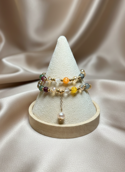 Set of bracelets on a white cone-shaped jewelry stand against a beige fabric background