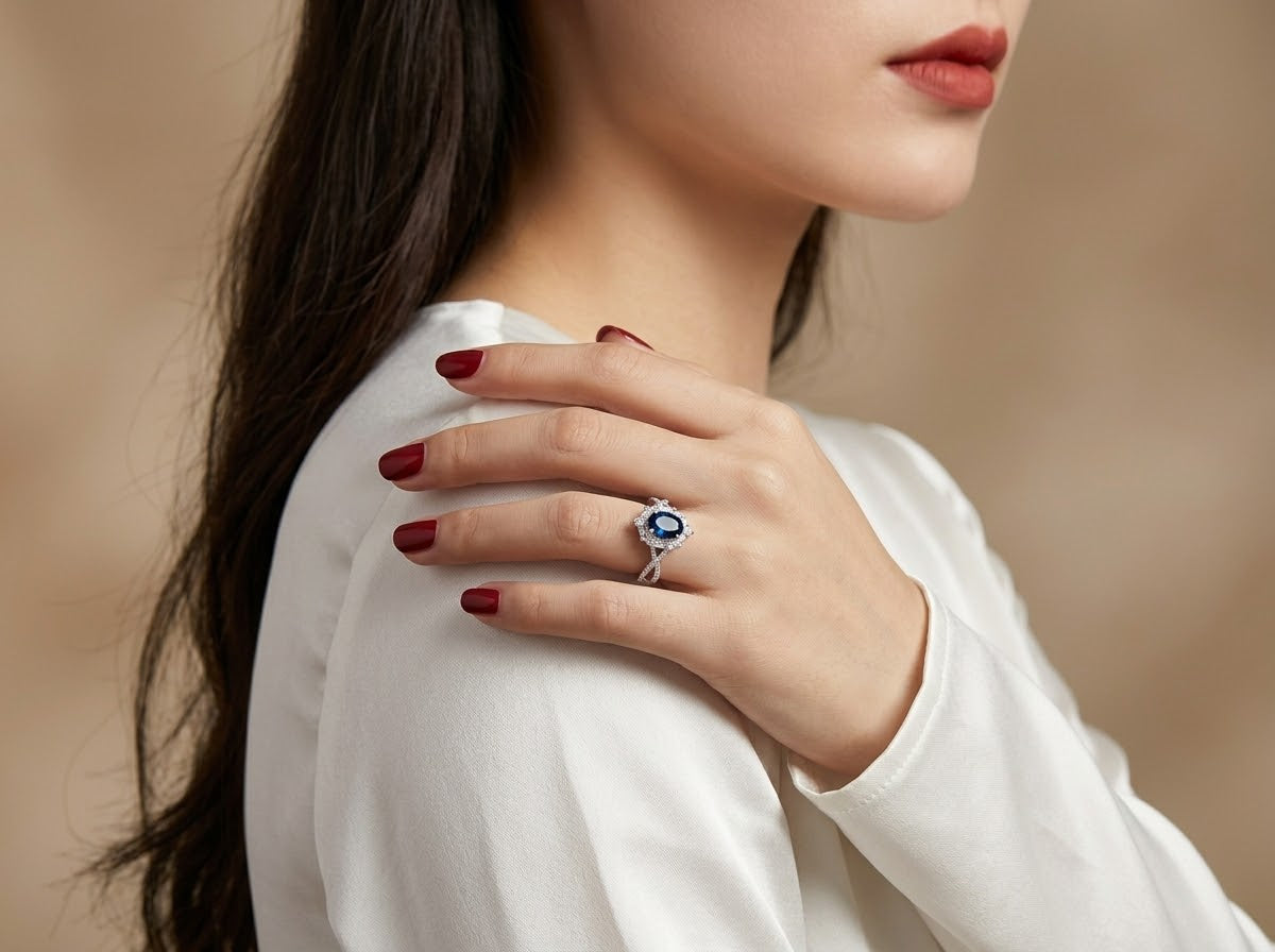 A close-up lifestyle shot of a woman wearing a silver ring with a blue oval gemstone, resting her hand on her shoulder.
