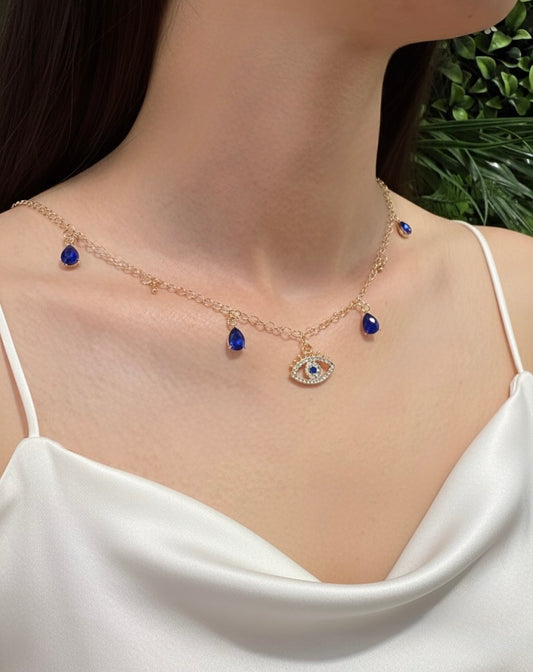 close up gold plated evil eye necklace with blue teardrop charms