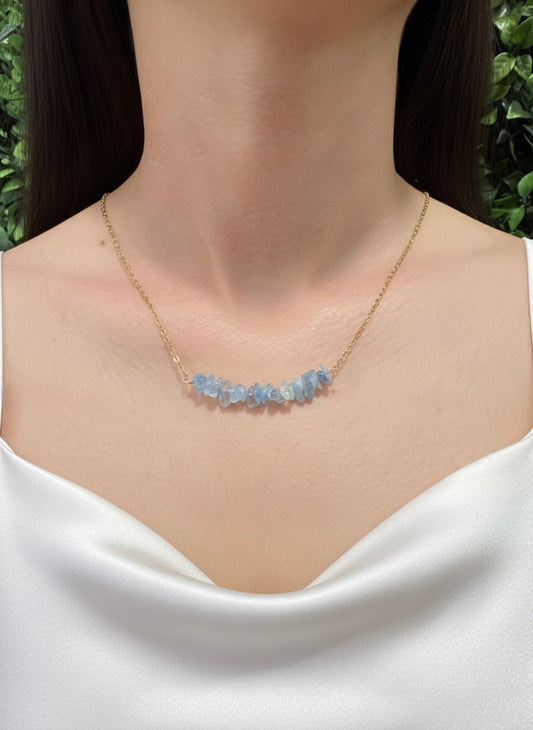 Necklace with blue gemstones worn by a model against a green leafy background