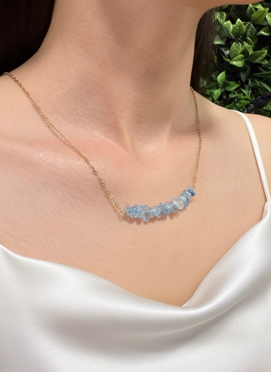 Necklace with blue gemstones worn by a person against a blurred green background