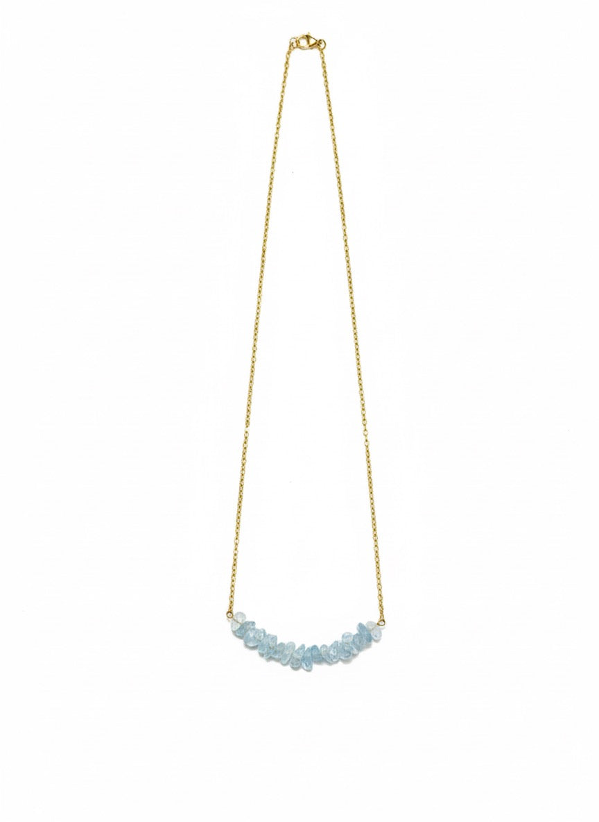 Necklace with blue gemstones on a gold chain against a white background